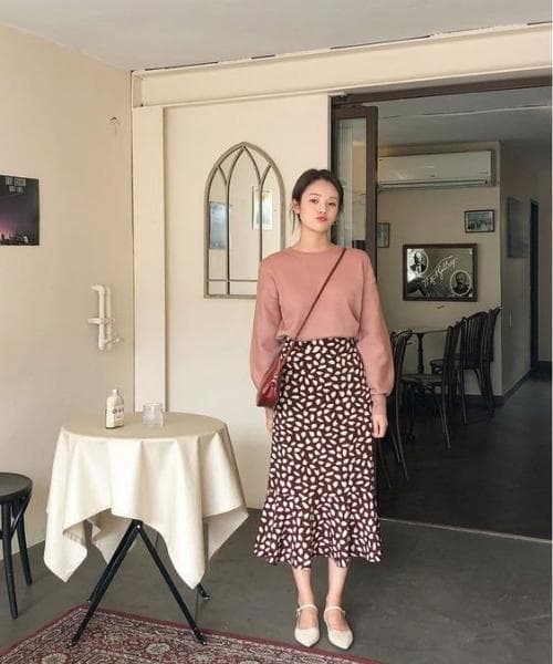 ผู้หญิงเอเชียใส่เสื้อสเวตเตอร์แขนยาวและกระโปรงยาว